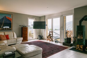 Un salón espacioso con un amplio ventanal, un televisor de pantalla plana, un sofá, un mueble de madera y una chimenea.
