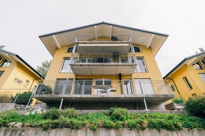 Un edificio amarillo de varios pisos con balcones, techo plano y base de concreto.