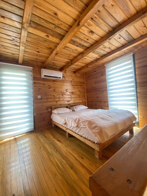 A wooden cabin room with a bed, a bench, and a window with blinds. - Agva Riverside Bungalow (Şile)