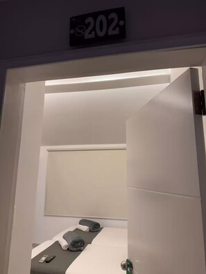 Une chambre d’hôtel avec un lit, une table de chevet et un panneau fixé au mur indiquant le numéro de chambre : 202.