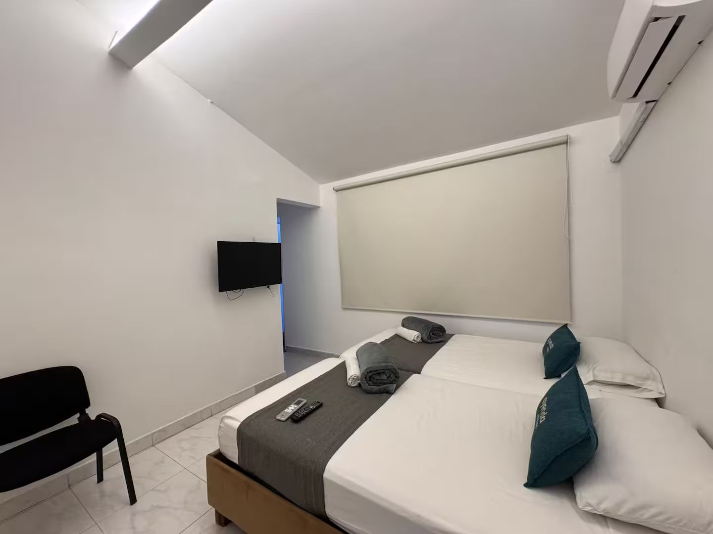 A modern hotel room with a bed, a TV mounted on the wall, and a window with a view.