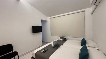 A modern hotel room with a bed, a TV mounted on the wall, and a window with a view.