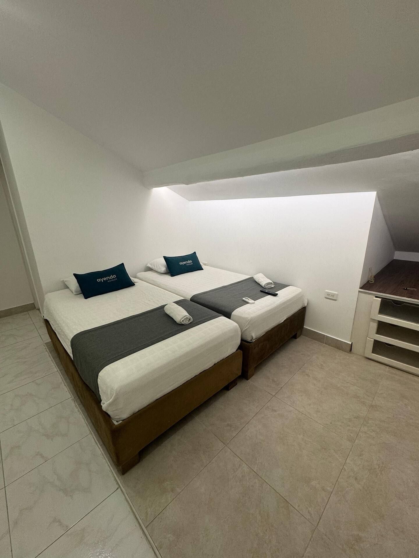 Een hotelkamer met twee bedden, een bureau en een klein keukenblok.