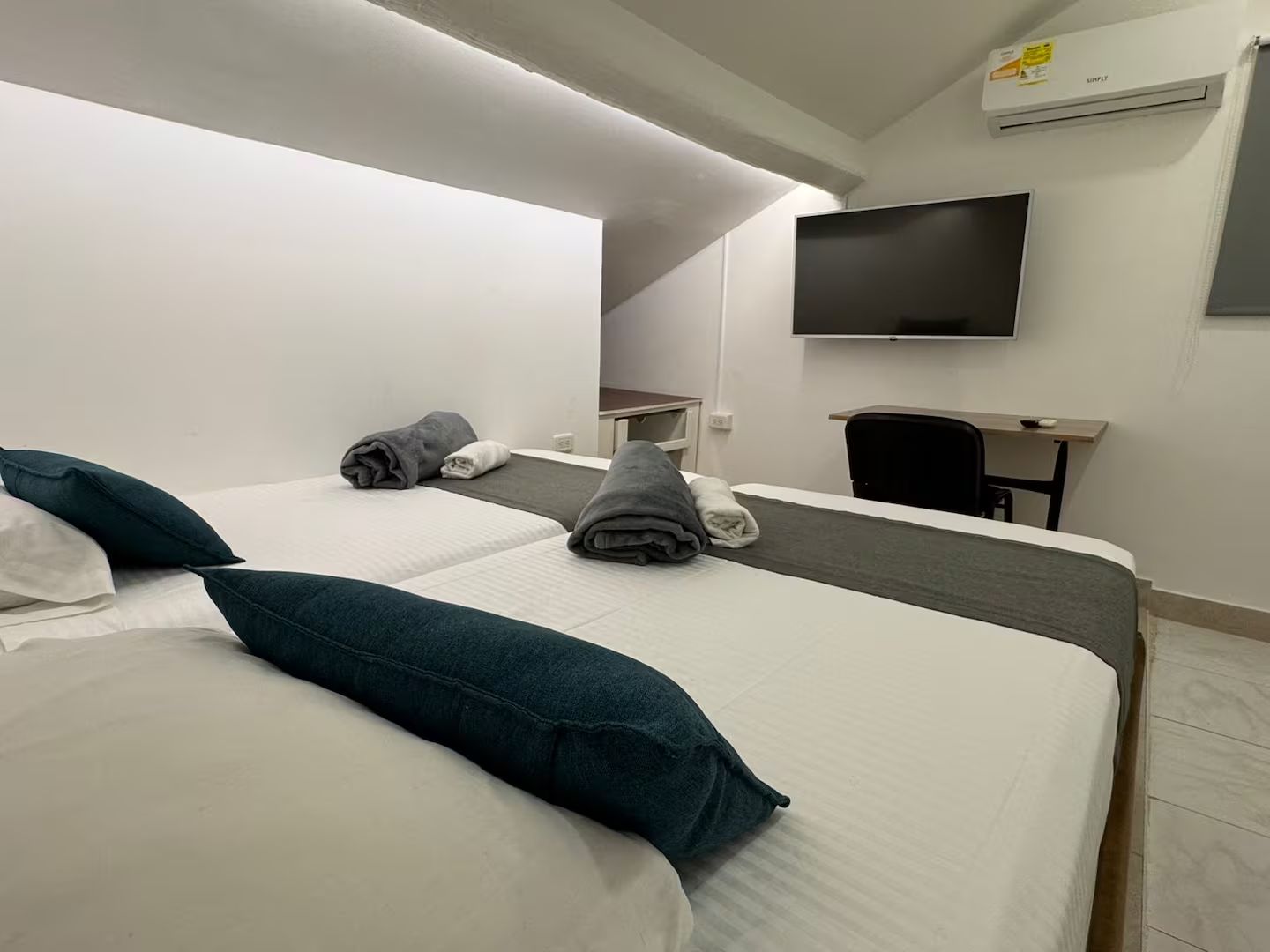 Een hotelkamer met een bed, een bureau, een stoel, een flatscreen televisie en een airconditioning.