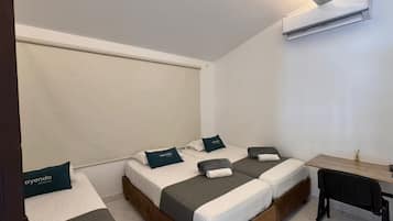 A hotel room with two beds, a desk, and an air conditioning unit.