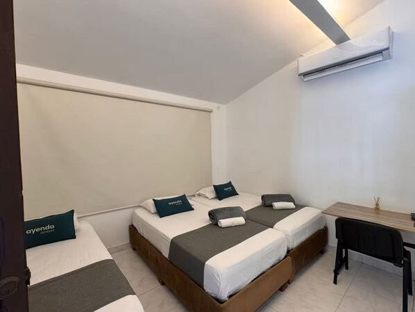 Une chambre d’hôtel avec deux lits, un bureau et un appareil de climatisation.