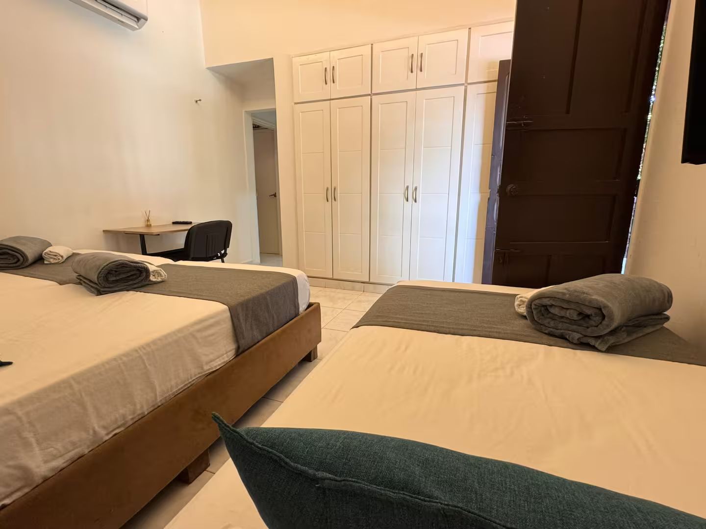 A hotel room with two beds, a desk, and a wardrobe.