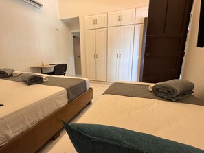 Une chambre d’hôtel avec deux lits, un bureau et une armoire.