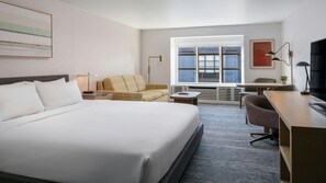 A hotel room with a large bed, a sofa, a desk, and a television. - Marriott Vacation Club San Francisco - Cozy City Room with Courtyard Fire Pit (San Francisco)