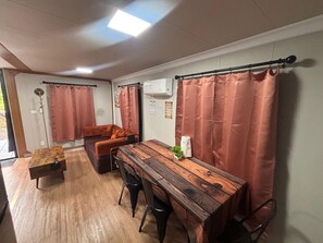 A room with a wooden dining table, a sofa, and a small table with a plant.