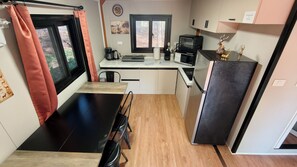 Una cocina compacta con una mesa de comedor, un refrigerador, un microondas y una cafetera.