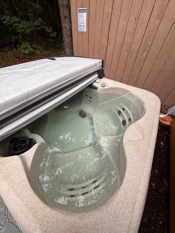 Un jacuzzi con plataforma de madera y un cartel de seguridad.
