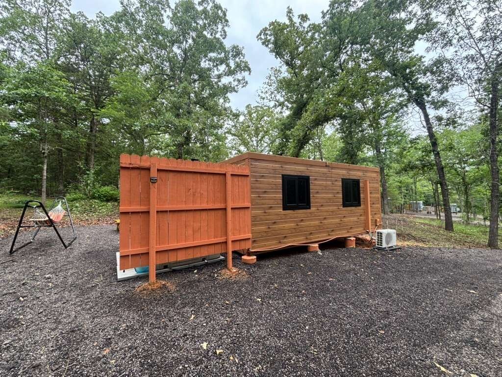 A wooden structure with a fenced area, a small window, and a gravel ground.