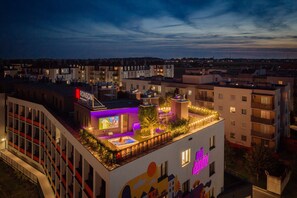 A rooftop terrace with a bar area, outdoor seating, and a pool.