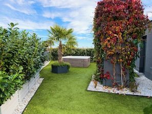 A well-maintained garden with a variety of plants, a palm tree, and a modern outdoor seating area.