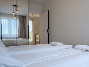 A hotel room with a large bed, a mirror, and a view of the outside.