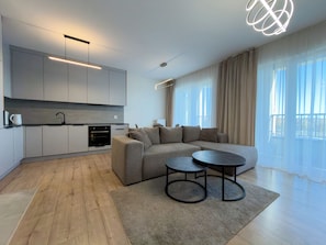 A modern living space with a kitchen, a sectional sofa, and a round coffee table.