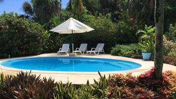 A swimming pool with three lounge chairs and a white umbrella.