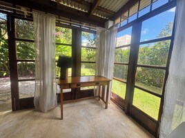 Una habitación con una mesa de madera, ventanas grandes y cortinas.