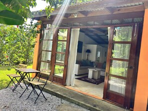 A wooden structure with a covered porch, a dining area with a table and chairs, and a view of a garden. - CB Tropical Paradise (Cabrera)