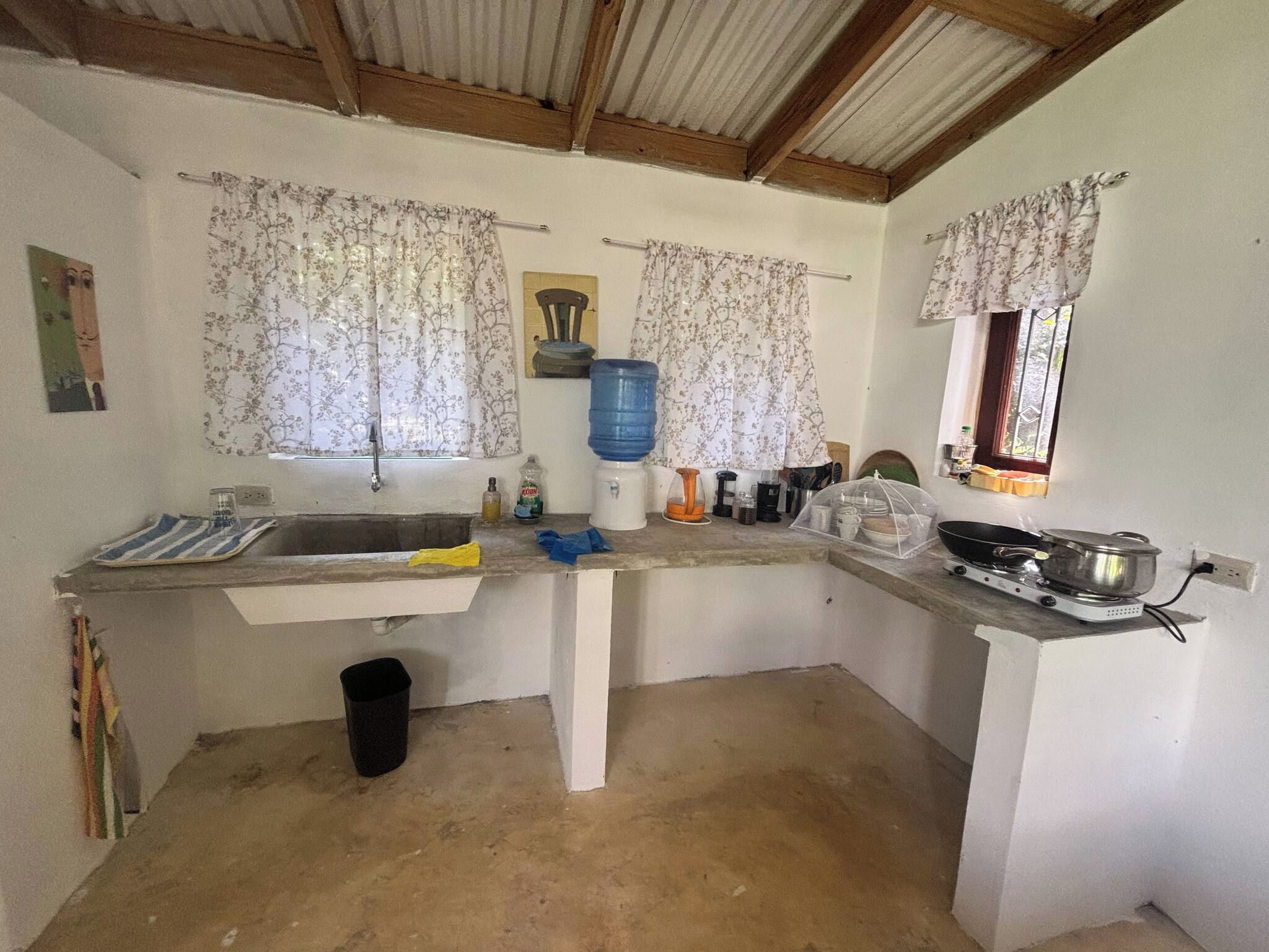 A compact kitchen with a sink, a water dispenser, and a stove.