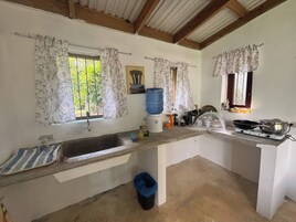 Una cocina con un lavamanos, dispensador de agua y estufa.