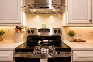 Una cocina con estufa de acero inoxidable, campana de cristal y salpicadero de mármol.