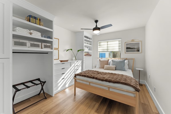 A bedroom with a bed, a wardrobe, a desk, and a window.