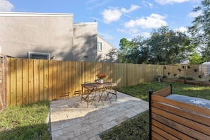 A patio area with a wooden table and chairs, a potted plant, and a wooden fence.