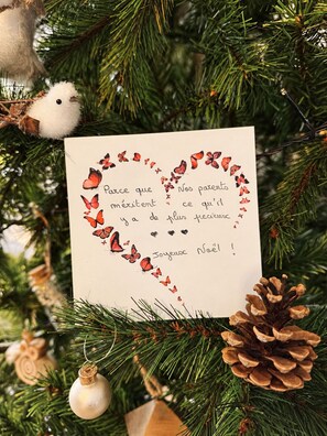 Eine Weihnachtskarte mit Herzform aus Schmetterlingen, auf einem Weihnachtsbaum platziert.