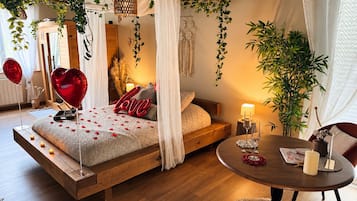 A bedroom with a bed, bedside table, and a round table with candles.