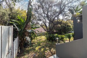 Un quartier résidentiel comprenant une maison, une cour clôturée et une variété de végétaux, notamment des arbres et des plantes.
