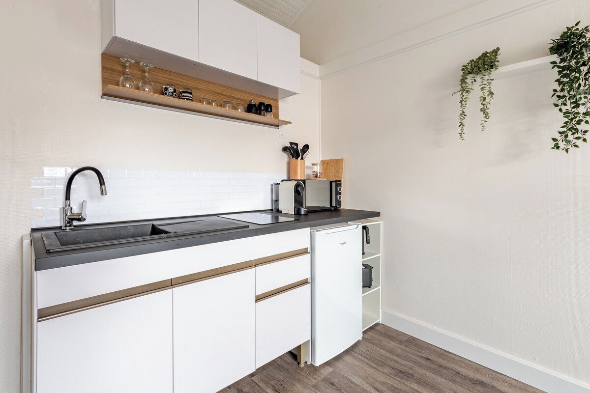 A modern kitchen with a black countertop, white cabinets, and a built-in dishwasher.