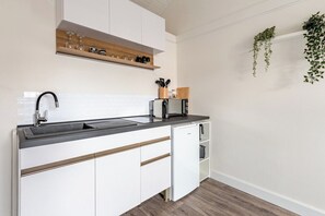 A modern kitchen with a black countertop, white cabinets, and a built-in dishwasher. - Brand-new design studio in Les Herbiers centre, covered parking (Les Herbiers)