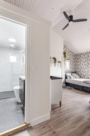 Un intérieur moderne comprenant une salle de bain, un lit et un ventilateur de plafond.