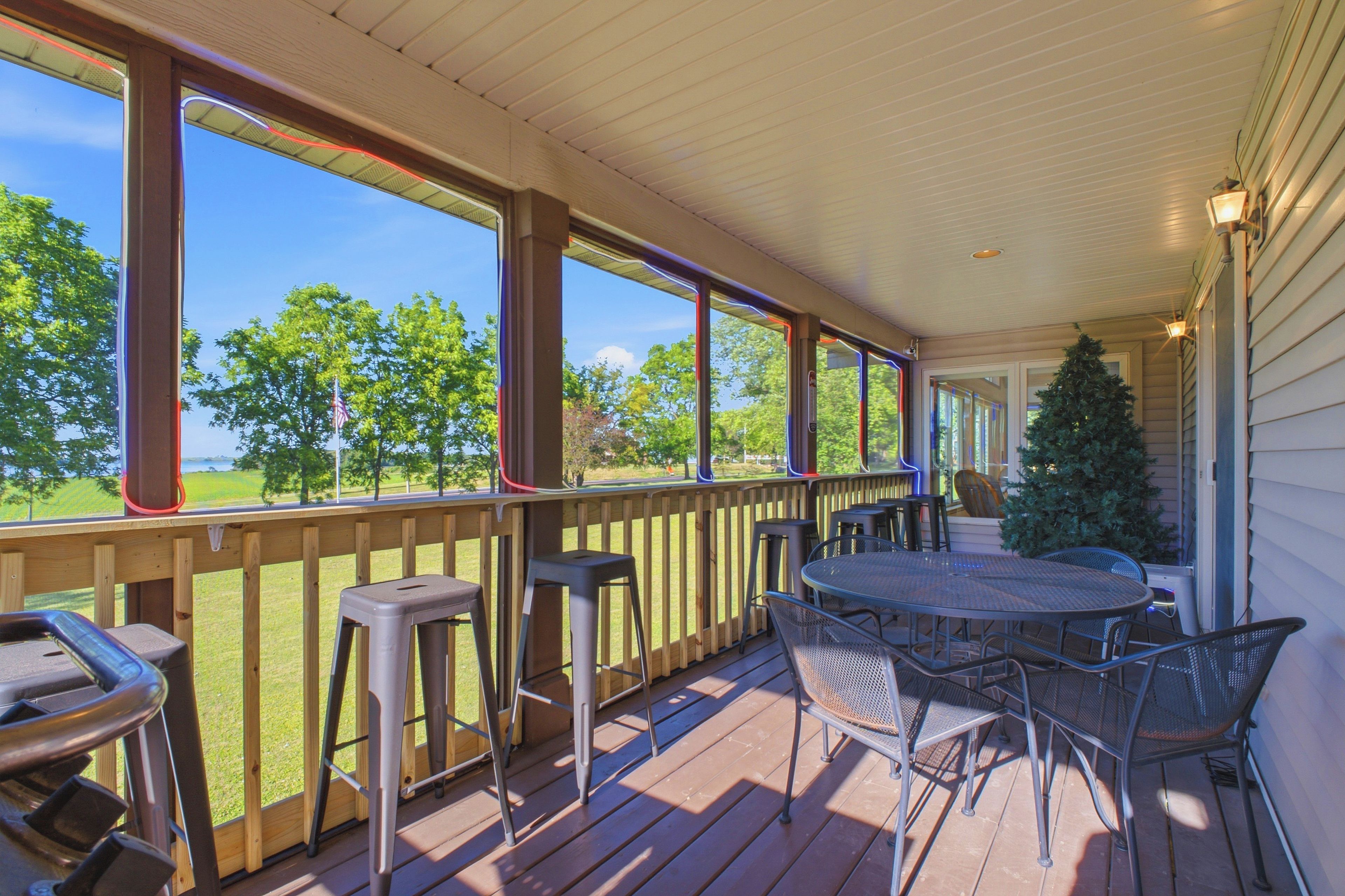 A covered outdoor deck with a table and chairs, a Christmas tree, and a view of the outdoors.