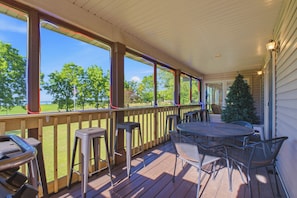 En overdækket terrasse med bord og stole, et juletræ og udsigt over landskabet.
