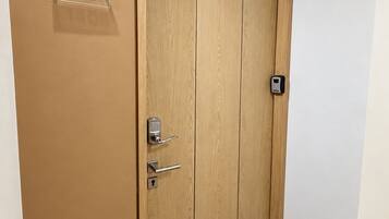 A wooden door with a numeric plaque, a keyhole, and a doorbell.