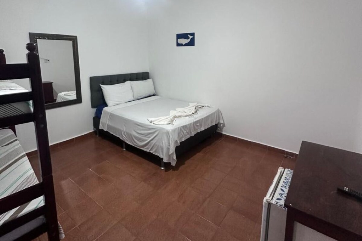 Una camera da letto con un letto, una scrivania, una sedia, una ventola a soffitto e uno specchio fissato alla parete.