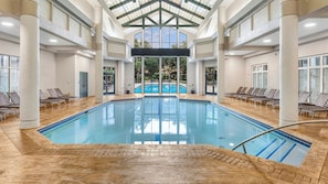 Una piscina interior con techo alto y amplios ventanales.