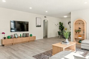 Ein modernes Wohnzimmer mit Flachbildfernseher, einem Holzunterschrank und einem Couchtisch.