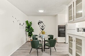 Et moderne køkken med hvide skabe, indbygget ovn og køleskab.