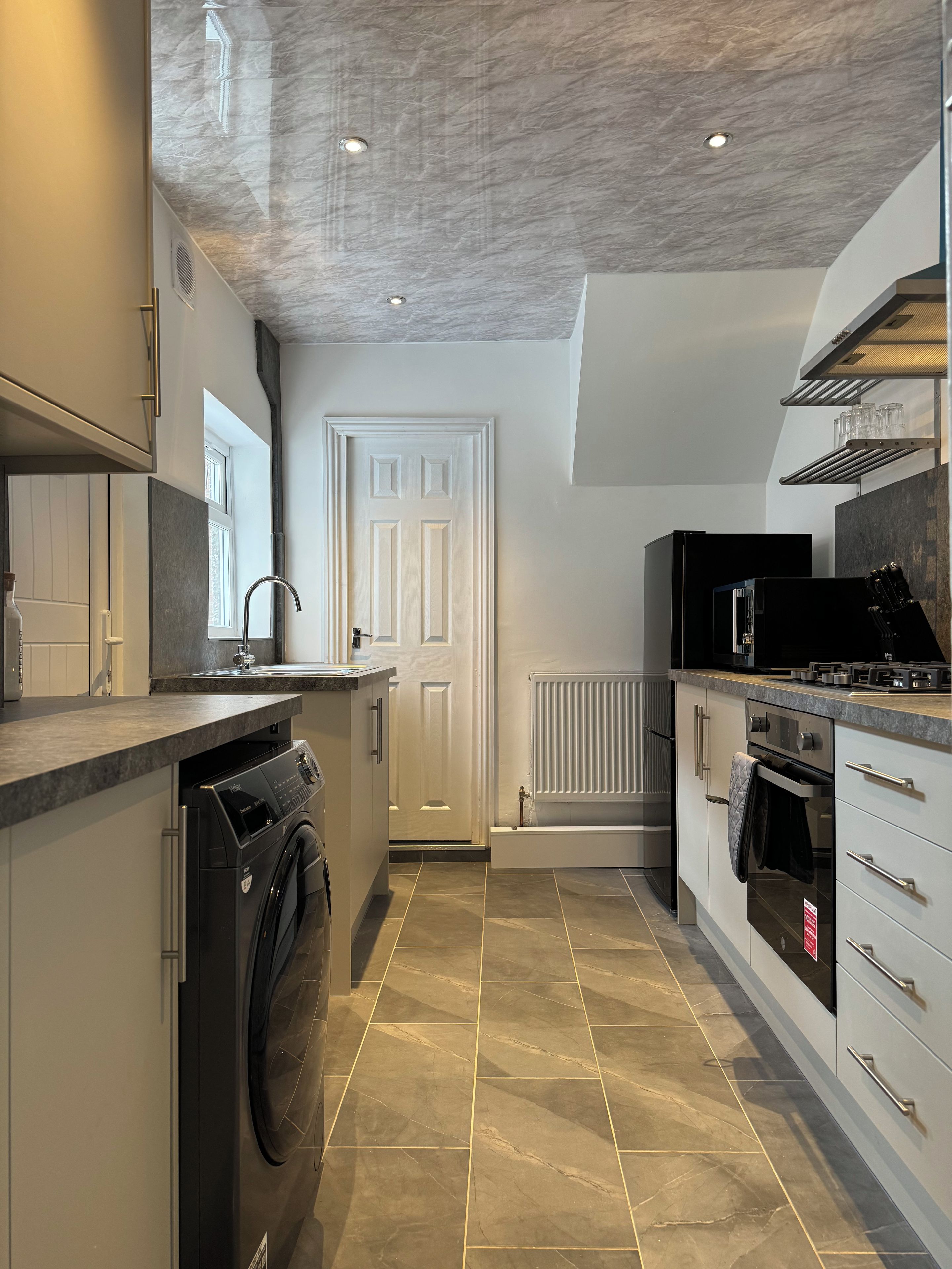 A modern kitchen with a built-in washer, a stove, and a microwave.