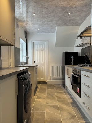 A modern kitchen with a built-in washer, a stove, and a microwave. - 2 Bedroom Flat - Central Location nearby Gateshead stadium metro line (Gateshead)