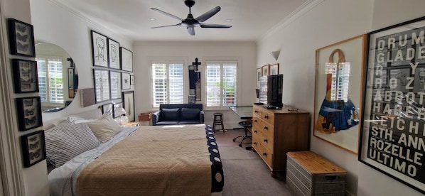 Une chambre à coucher comprenant un lit, un bureau, une chaise, une armoire et un ventilateur de plafond.
