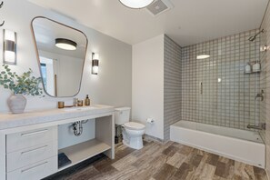 A modern bathroom with a vanity, toilet, and shower area.