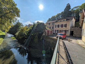 A river flowing through a town with buildings on the right and trees on the left. - New Listing (Charolles)