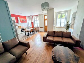 A spacious living area with a wooden floor, a brown leather sofa, and a dining table with chairs. - New Listing (Charolles)