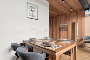 Een eethoek met een houten tafel, grijs gestoffeerde stoelen en een lijstwerk met een afbeelding aan de muur.
