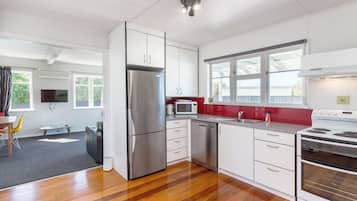 A modern kitchen with stainless steel appliances, a dishwasher, and a red backsplash.